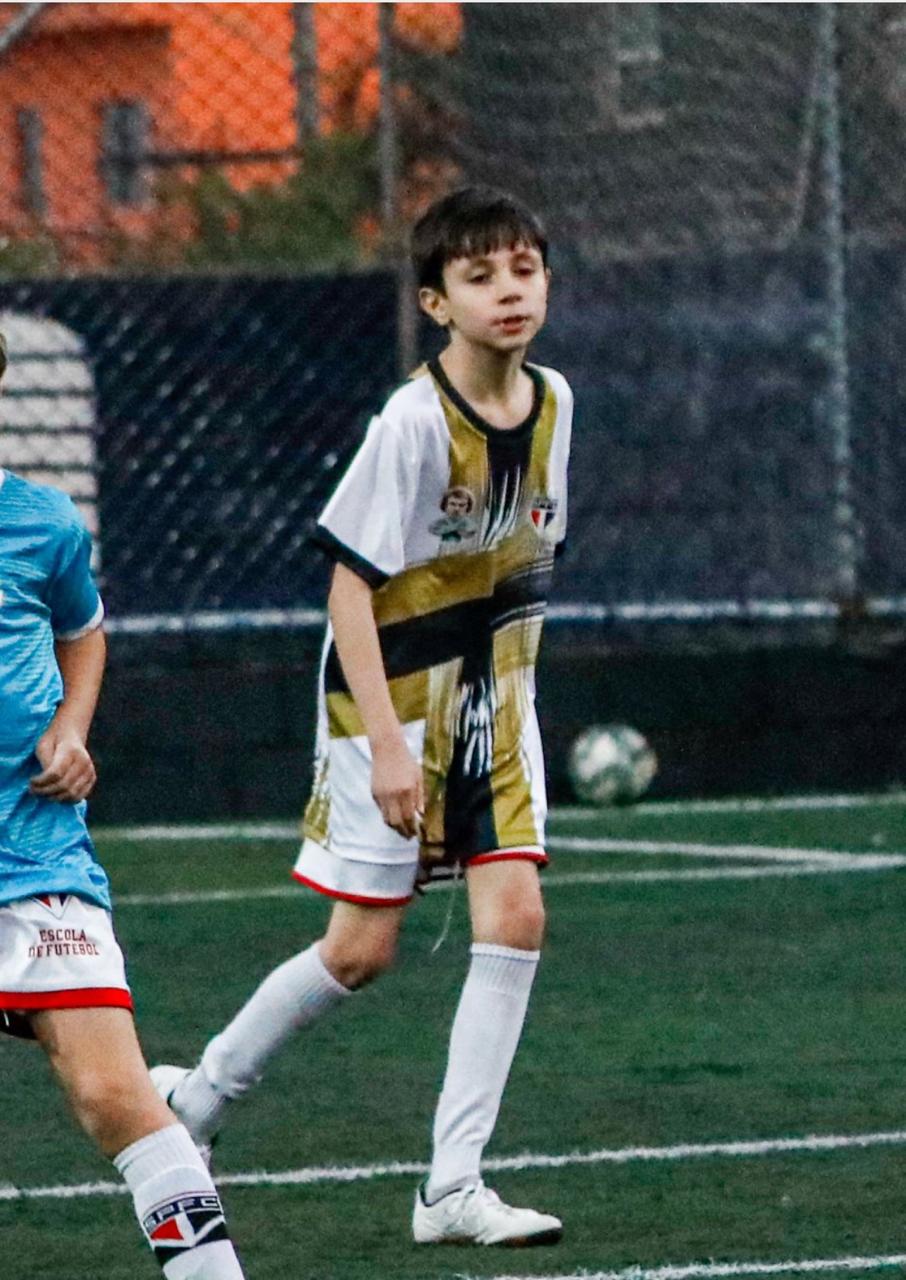 Diego jogando futebol com uniforme branco e dourado